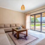 Salon avec canapé d’angle et baie vitrée donnant sur la piscine de la Villa Jnan Mogador.