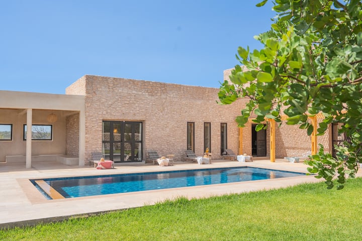 Vue de la piscine et de la façade de la Villa Jnan Mogador depuis le jardin.