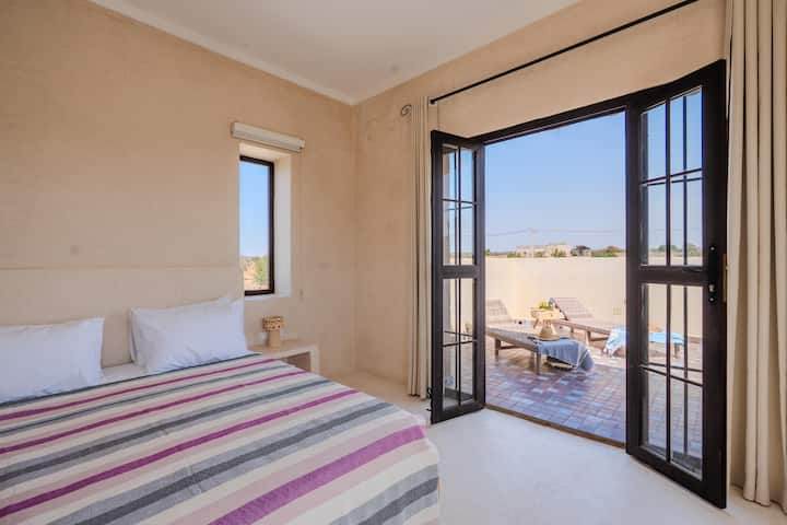 Chambre double de la Villa Jnan Mogador avec portes vitrées ouvertes sur la terrasse.